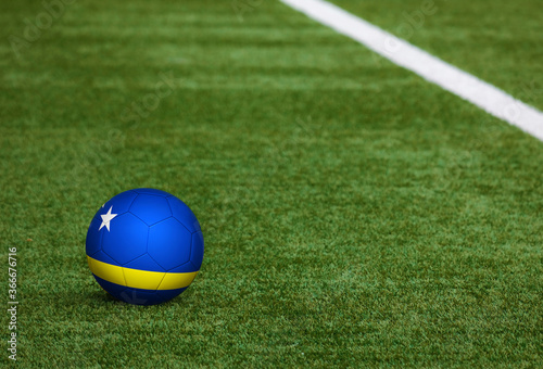 Curacao flag on ball at soccer field background. National football theme on green grass. Sports competition concept.