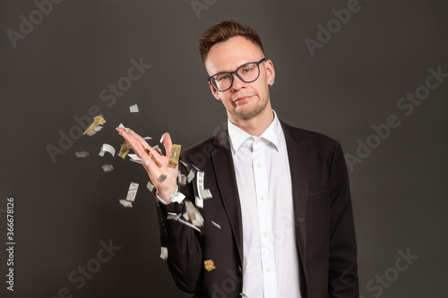 Disappointed birthday guy. Boring party. Annoyed dissatisfied business man throwing confetti isolated on dark. Loser portrait. Ruined celebration. Fake fun.