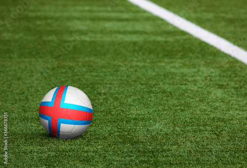 Faroe Islands flag on ball at soccer field background. National football theme on green grass. Sports competition concept.