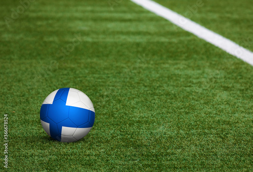 Finland flag on ball at soccer field background. National football theme on green grass. Sports competition concept.