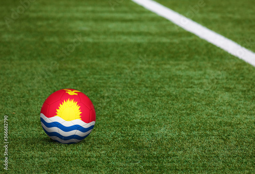 Kiribati flag on ball at soccer field background. National football theme on green grass. Sports competition concept.