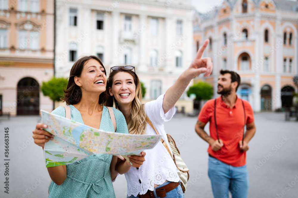 Happy traveling tourists sightseeing with map in hand Happy traveling tourists sightseeing with map in hand