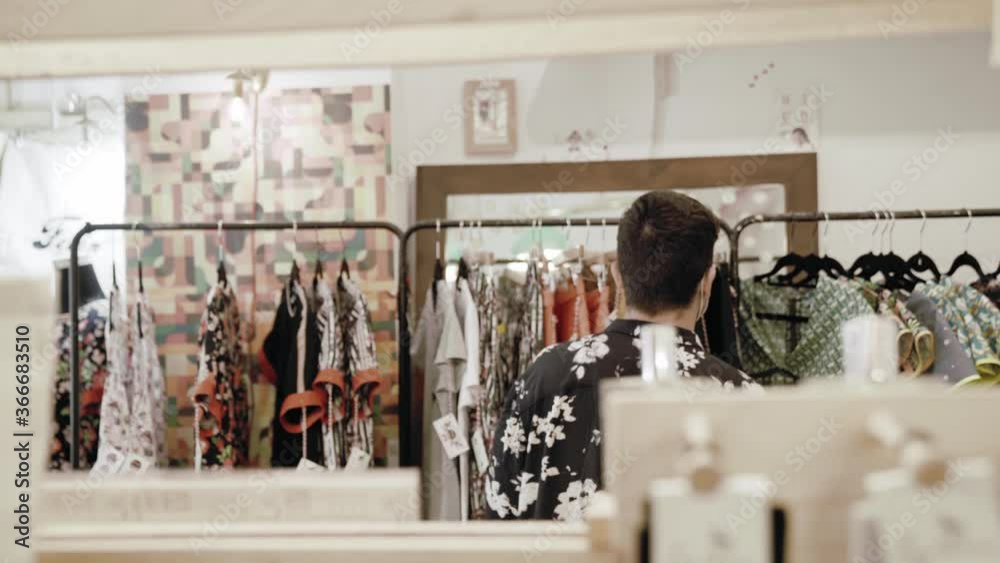 Hombre caucásico con camisa vintage comprando ropa en una tienda de ropa vintage con mascarilla covid coronavirus
