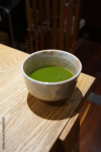 Close up ceramic cup of hot Matcha green tea on wooden table
