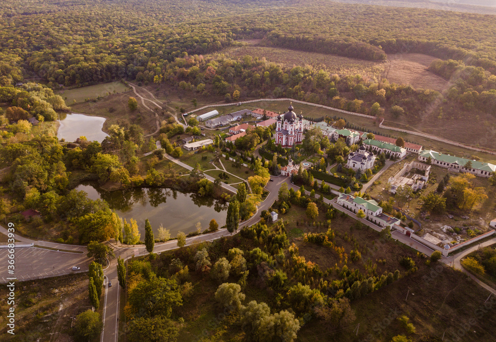 Flight over a christian monastery surrounded by autumn forest. Kurky monastery, Moldova republic of.