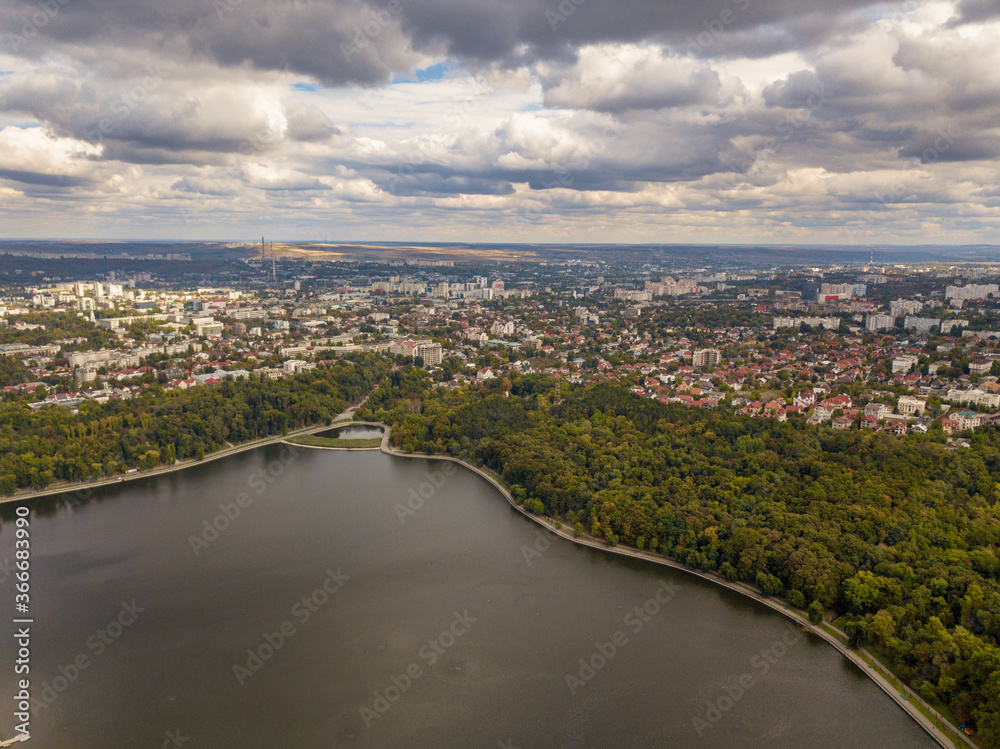 Aerial view of a lake in a park with autumn trees. Kishinev, Moldova. Epic aerial flight over water. Colorful autumn trees in the daytime.