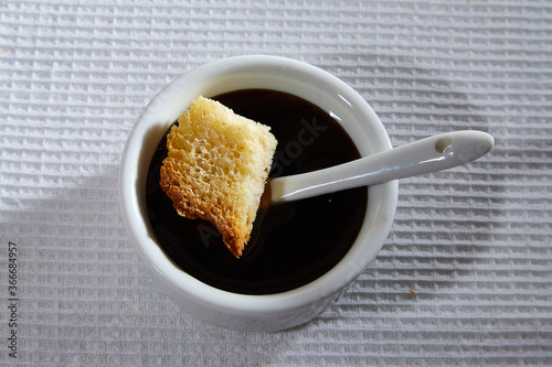 Liquid honey in a white plate and Square toasted piece of homemade delicious rusk, hardtack, Dryasdust, zwieback on a white tablecloth. photo