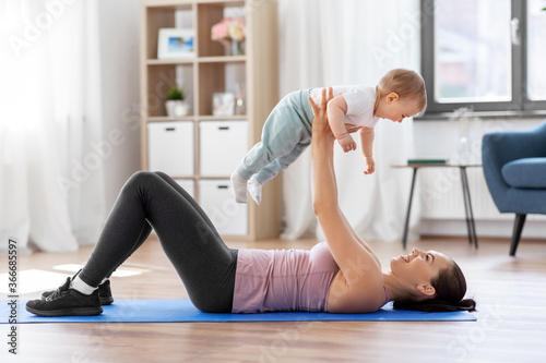 family, sport and motherhood concept - happy smiling mother with little baby exercising at home