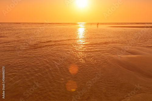 A colorful sunset or sunrise on the seaside with a sandy beach with impurities of volcanic ash. Mandrem, Goa, India. photo