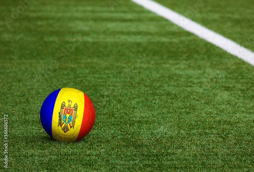 Moldova flag on ball at soccer field background. National football theme on green grass. Sports competition concept.