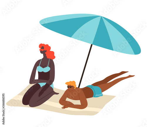 Couple relaxing by seaside sitting in shade of umbrella