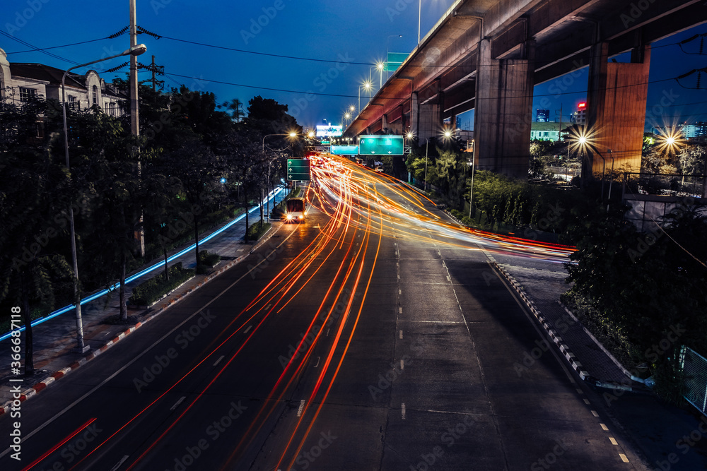 Car lights at night on the road going to the city. Aerial view of the speed traffic trails on motorway highway in Bang Kho Laem, Rama 3, Bangkok, Thailand. Long exposure abstract urban background.