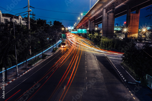 Car lights at night on the road going to the city. Aerial view of the speed traffic trails on motorway highway in Bang Kho Laem, Rama 3, Bangkok, Thailand. Long exposure abstract urban background.