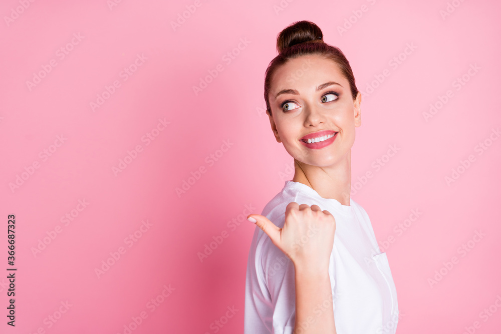 Closeup profile photo of attractive lady funny bun hairdo direct thumb finger side empty space show sale discount shopping season wear white t-shirt isolated pastel pink color background Closeup profile photo of attractive lady funny bun hairdo direct thumb finger side empty space show sale discount shopping season wear white t-shirt isolated pastel pink color background