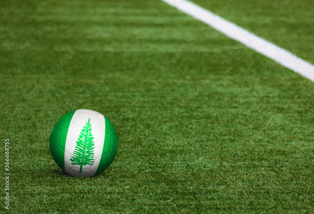 Naklejka Flaga wyspy Norfolk na piłkę w tle boisko do piłki nożnej. Narodowy motyw piłki nożnej na zielonej trawie. Koncepcja zawodów sportowych.