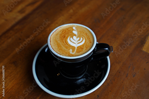 Close up ceramic cup of hot Latte coffee art on wooden table