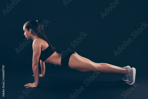 Profile side view of her she nice-looking attractive sportive focused concentrated purposeful lady staying in plank pose on floor perfect form shape figure line isolated over black background