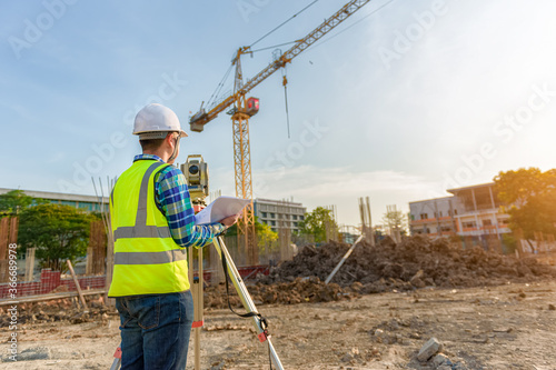 Surveying engineers are working together using theodolite on the construction site. © VR Studio