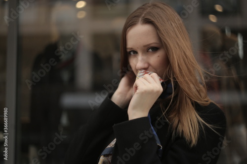 The girl in black coat. Beautiful emotional young girl in the city. Shawl or handkerchief on a person. 