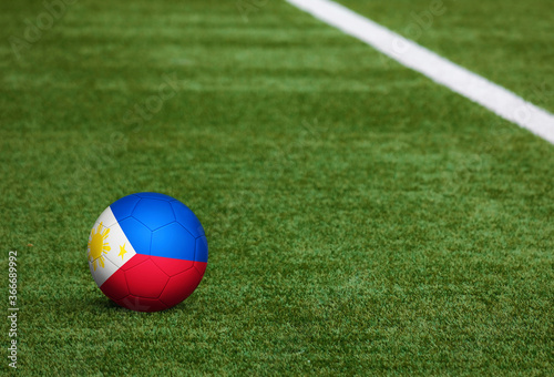 Philippines flag on ball at soccer field background. National football theme on green grass. Sports competition concept.