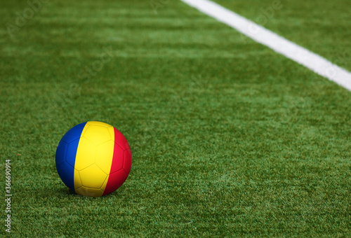 Romania flag on ball at soccer field background. National football theme on green grass. Sports competition concept.