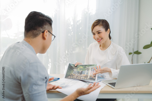 Young Asian man at real estate agent in office with famale seller.