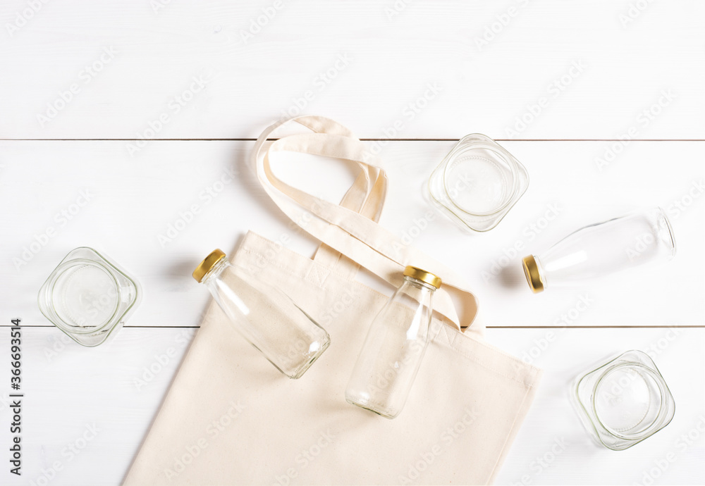 Reusable woven bag and glass bottles and jars, lie on a white background, set for shopping without waste. Eco-friendly lifestyle. Horizontal orientation, copy space. Reusable woven bag and glass bottles and jars, lie on a white background, set for shopping without waste. Eco-friendly lifestyle. Horizontal orientation, copy space.