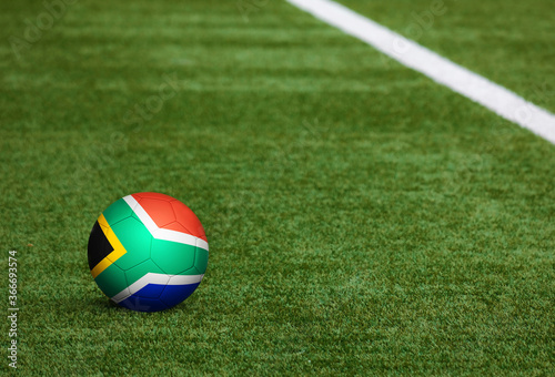 South Africa flag on ball at soccer field background. National football theme on green grass. Sports competition concept.