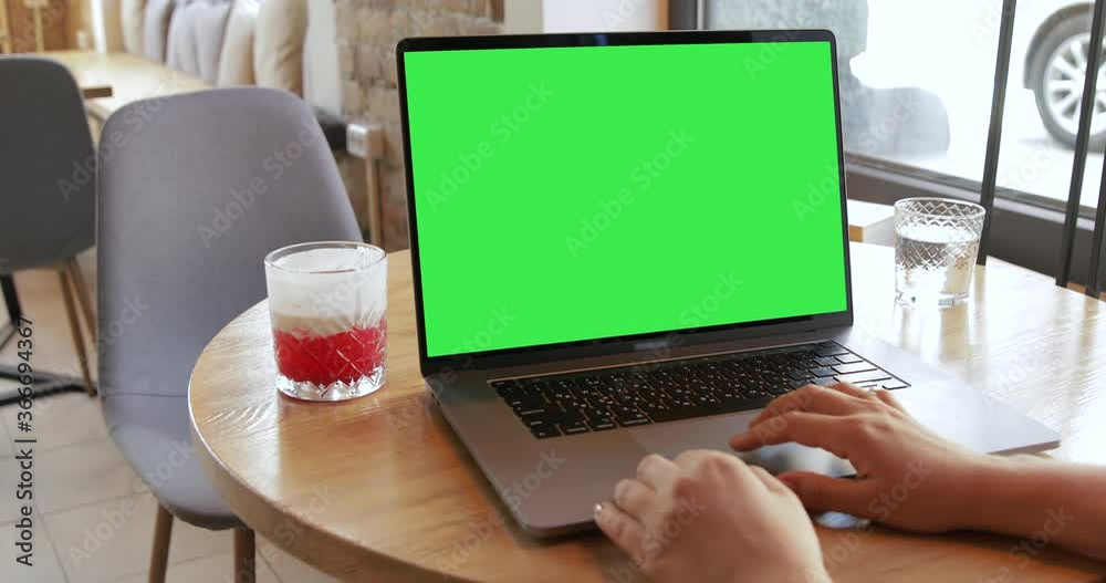 Girl hands typing keyboard MacBook Pro 16 inch computer in coffeeshop. Unrecognisable person working on laptop notebook green screen chromakey monitor. Mock-up blank display