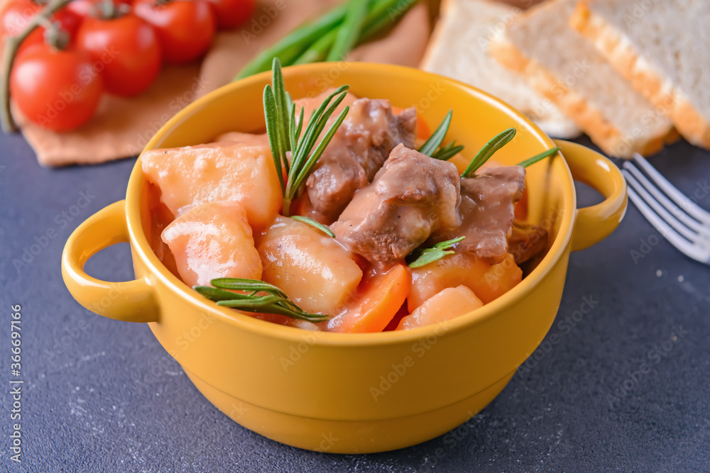 Pot with tasty beef stew on dark background Pot with tasty beef stew on dark background