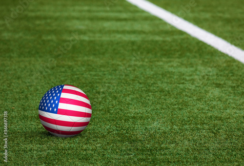 United States flag on ball at soccer field background. National football theme on green grass. Sports competition concept.