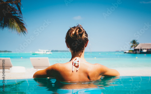 beautiful caucasian woman with slim body sunbathing and resting at resort pool on the white sand beach at summer © Vasily Makarov