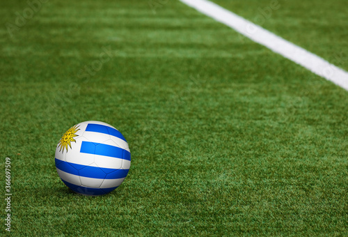 Uruguay flag on ball at soccer field background. National football theme on green grass. Sports competition concept. © sezerozger