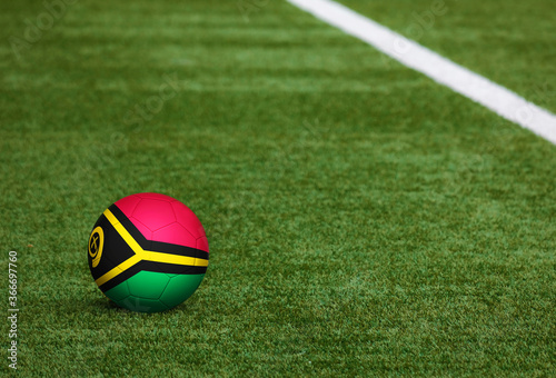 Vanuatu flag on ball at soccer field background. National football theme on green grass. Sports competition concept.