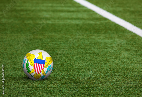 United States Virgin Islands flag on ball at soccer field background. National football theme on green grass. Sports competition concept.