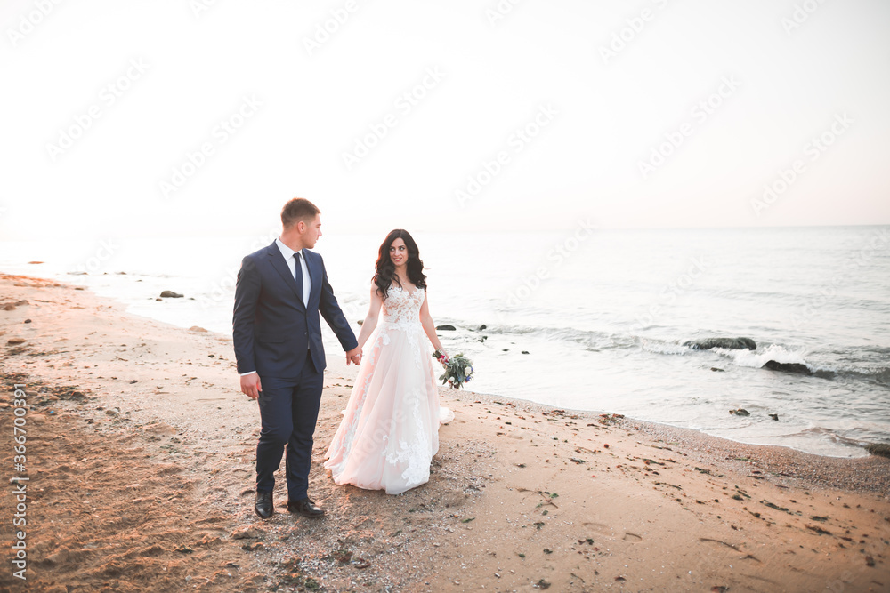 Happy and romantic scene of just married young wedding couple posing on beautiful beach Happy and romantic scene of just married young wedding couple posing on beautiful beach