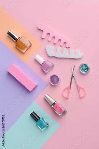 Nail varnishes and manicurist tools on multicolor background