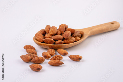 Almonds on wooden spoon isolated over white background