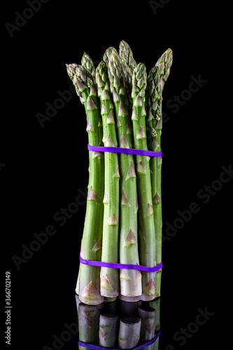 Asparagus. Bunch of fresh green asparagus tied on black background.