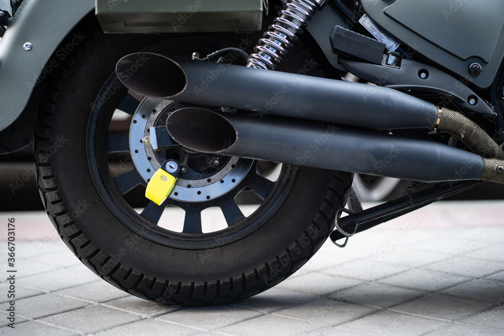 Cepo de seguridad anti robo fijado en el freno de disco de  la rueda trasera de una moto gris con 