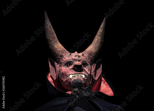 Devil with horns and in a black cloak on a dark background looks up. photo