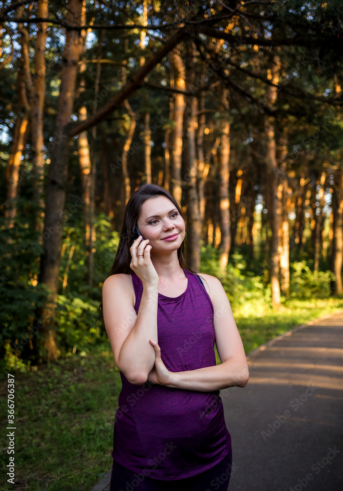 Beautiful brunette girl talking on the phone in the Park at sunset Beautiful brunette girl talking on the phone in the Park at sunset