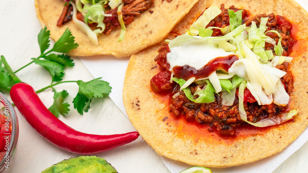 Mexican traditional authentic homemade tacos with pulled pork beef chili con carne serve with tomato salad and avocado guacamole and dip sauce Mexican traditional authentic homemade tacos with pulled pork beef chili con carne serve with tomato salad and avocado guacamole and dip sauce