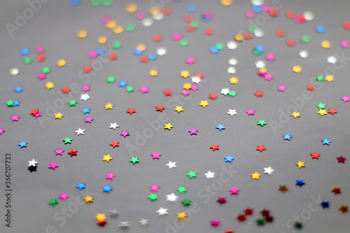 Colorful star shaped confetti on pale purple background. Selective focus.