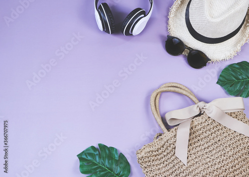 Travel and summer holiday concept, Women's vacation accessories items on purple background with tropical monstera leaves.top view