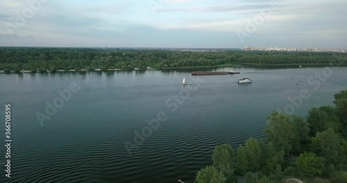 Drone flight over the river overlooking the tug barge and sailboat in the evening, sunset. Ukraine