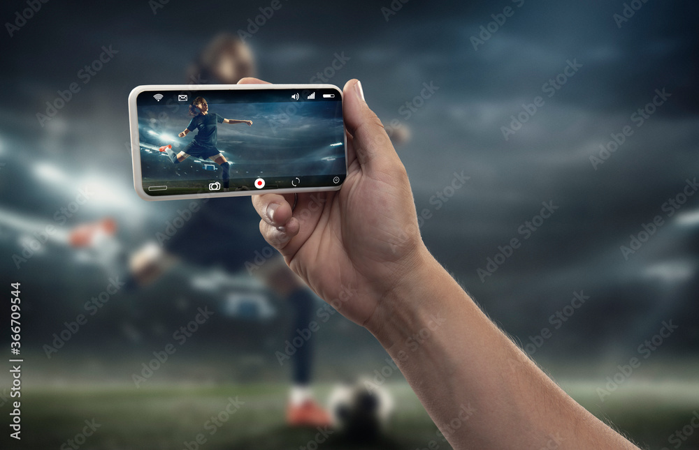 Close up hands holding smartphone viewing sport, football online streaming of championship. New rules during coronavirus outbreak and countries lockdown. Concept of sport, competition, technologies.