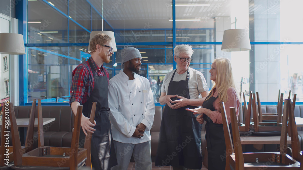 Multiethnic restaurant staff talking before opening Multiethnic restaurant staff talking before opening