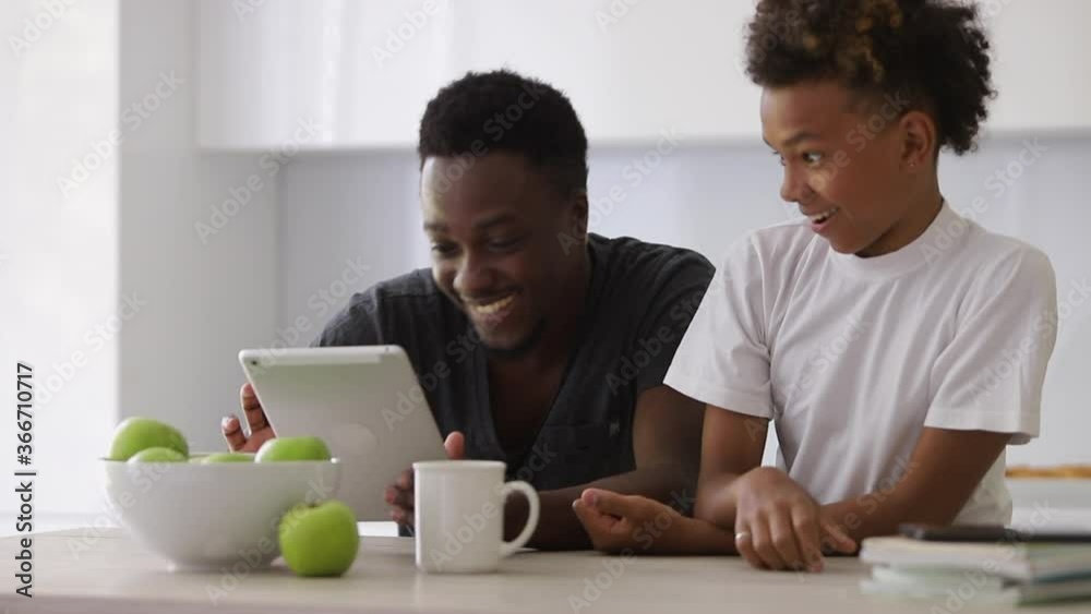 afro father showing son internet app movie website on tablet Spbi. surprised shocked expression. funny family communication and bonding. scrolling touchscreen and explaining game. afro father showing son internet app movie website on tablet Spbi. surprised shocked expression. funny family communication and bonding. scrolling touchscreen and explaining game.