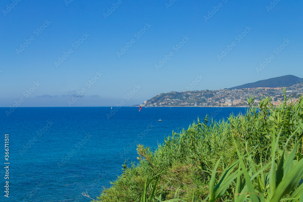 Waves against rock and, in the background, the italian coast with the city of Sanremo
